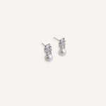 Pair of silver stud earrings with baguette crystal tops and pearl drops, displayed on a soft background.