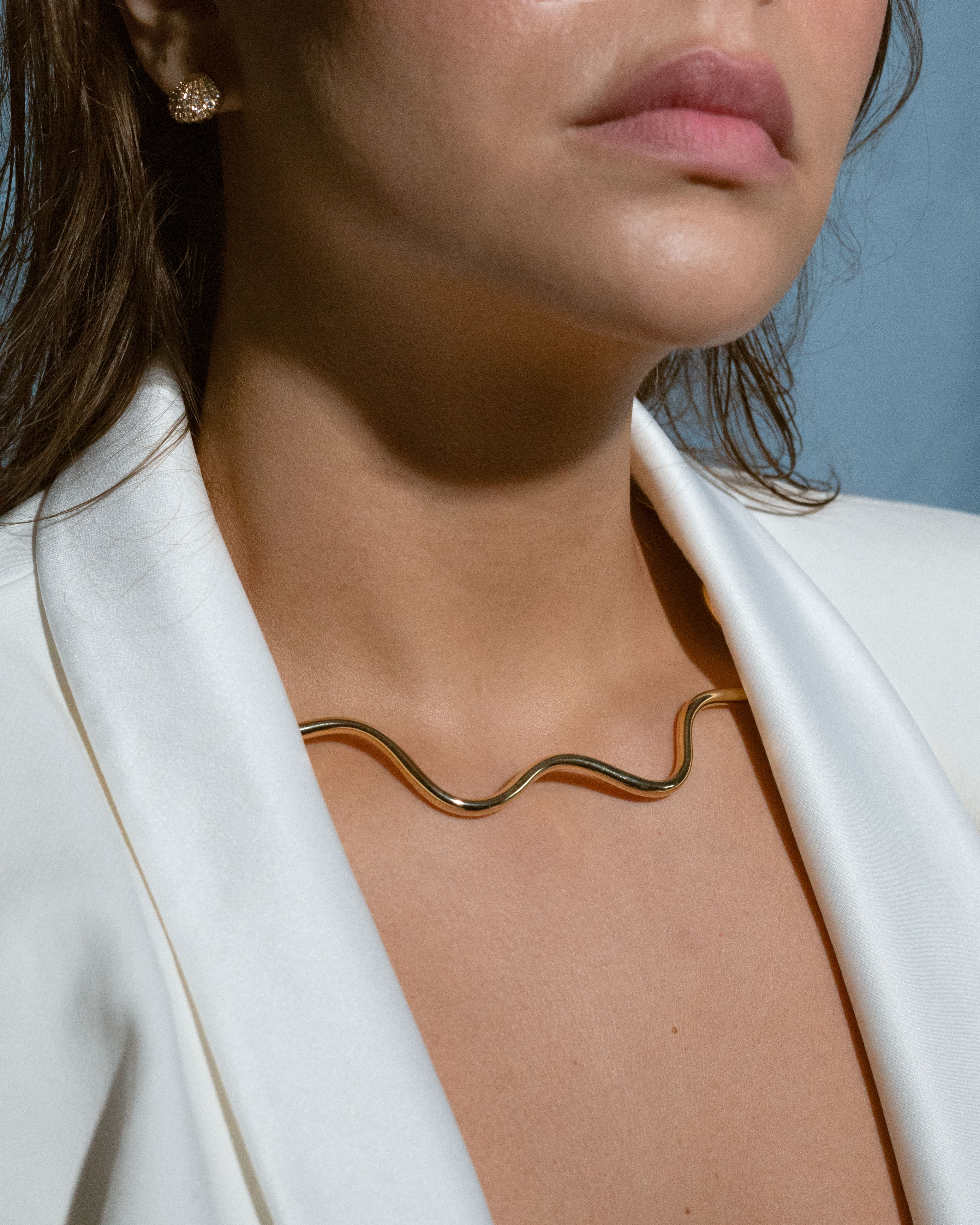 Gold-plated choker necklace with wavy, sculptural shape.