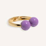Gold open cuff bracelet with large enamel beads in pink and purple, styled for casual daywear
