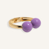 Gold open cuff bracelet with large enamel beads in pink and purple, styled for casual daywear