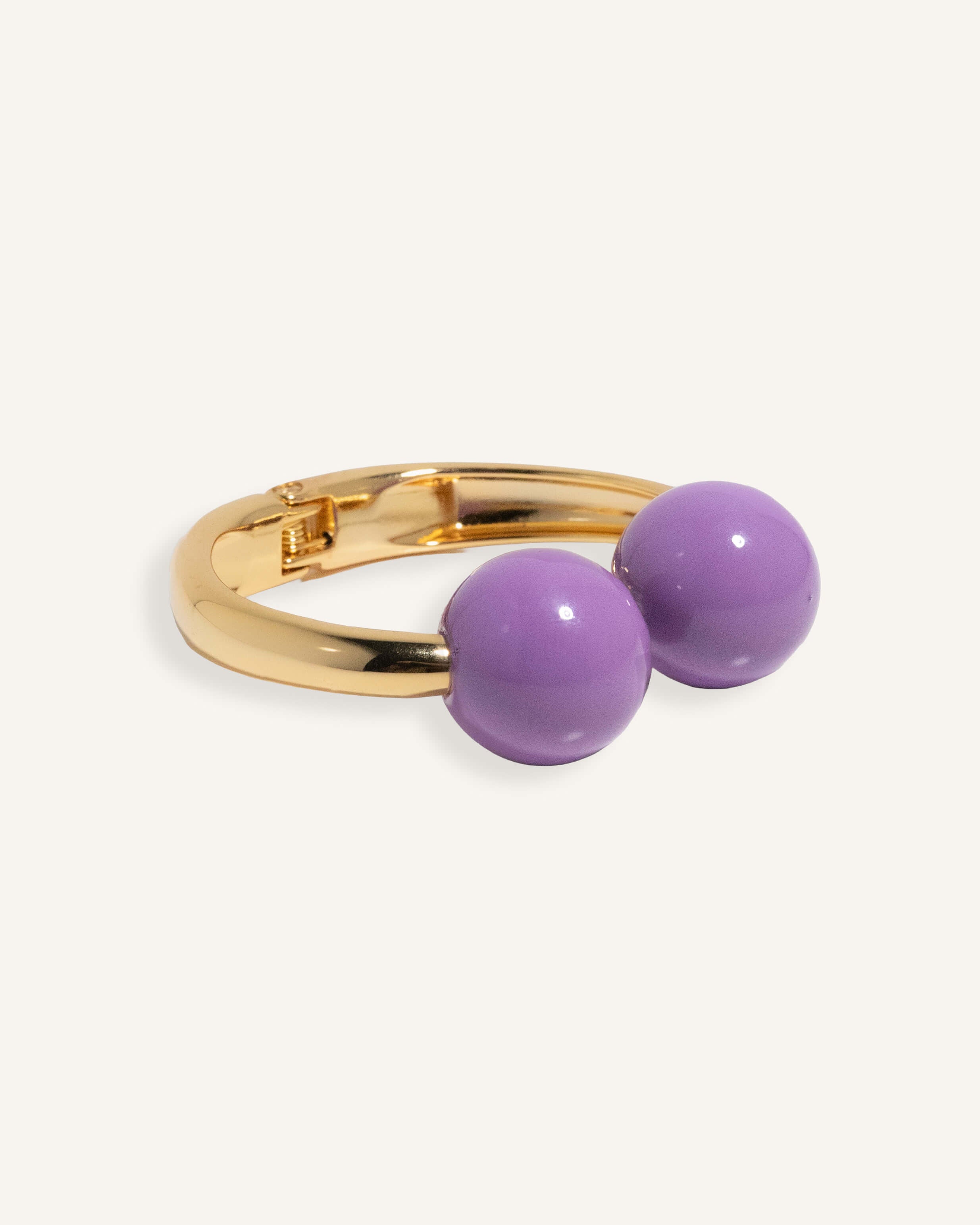 Gold open cuff bracelet with large enamel beads in pink and purple, styled for casual daywear