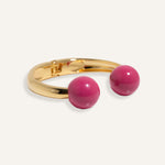 Gold open cuff bracelet with large enamel beads in pink and purple, styled for casual daywear..