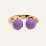 Gold open cuff bracelet with large enamel beads in pink and purple, styled for casual daywear.