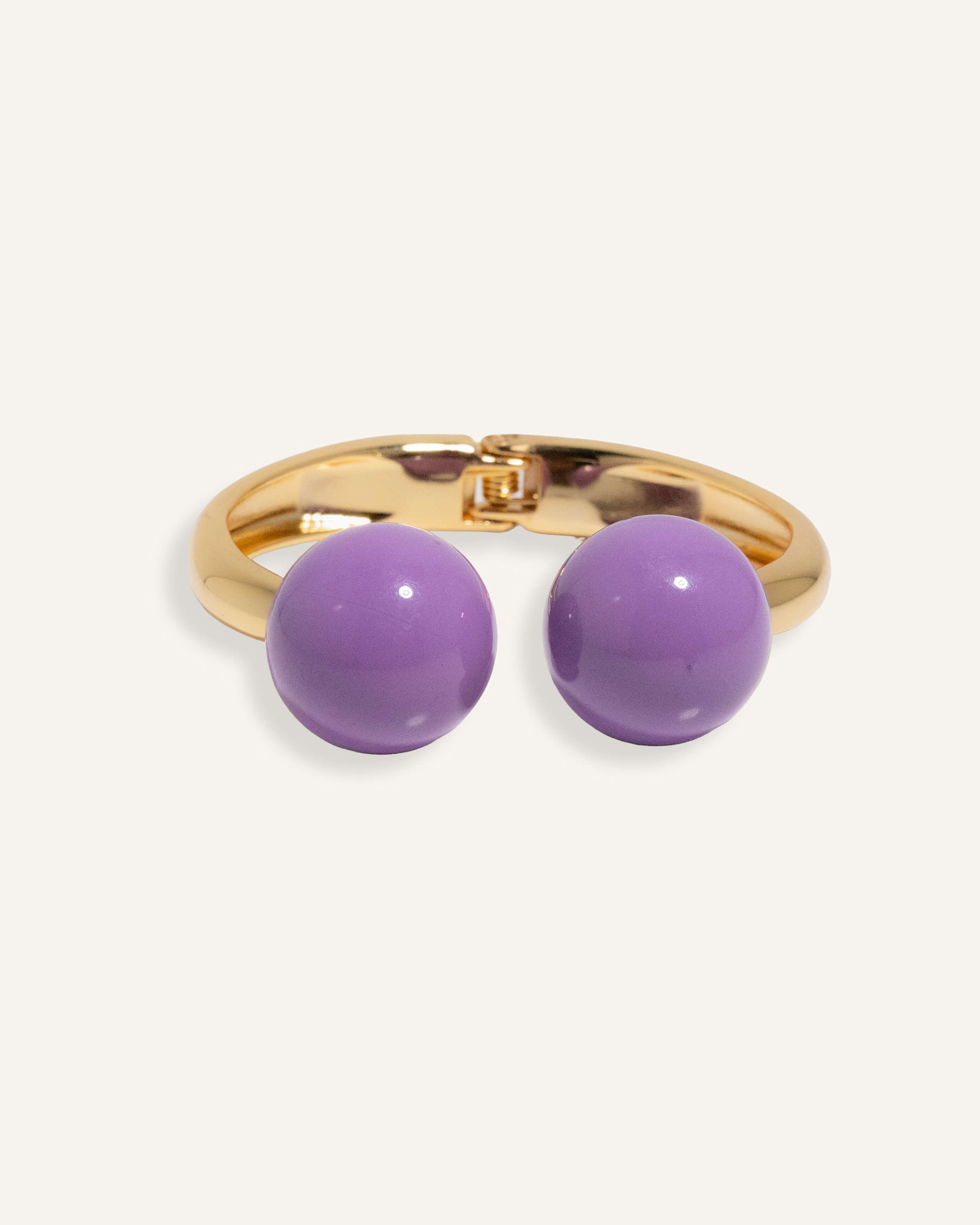 Gold open cuff bracelet with large enamel beads in pink and purple, styled for casual daywear.