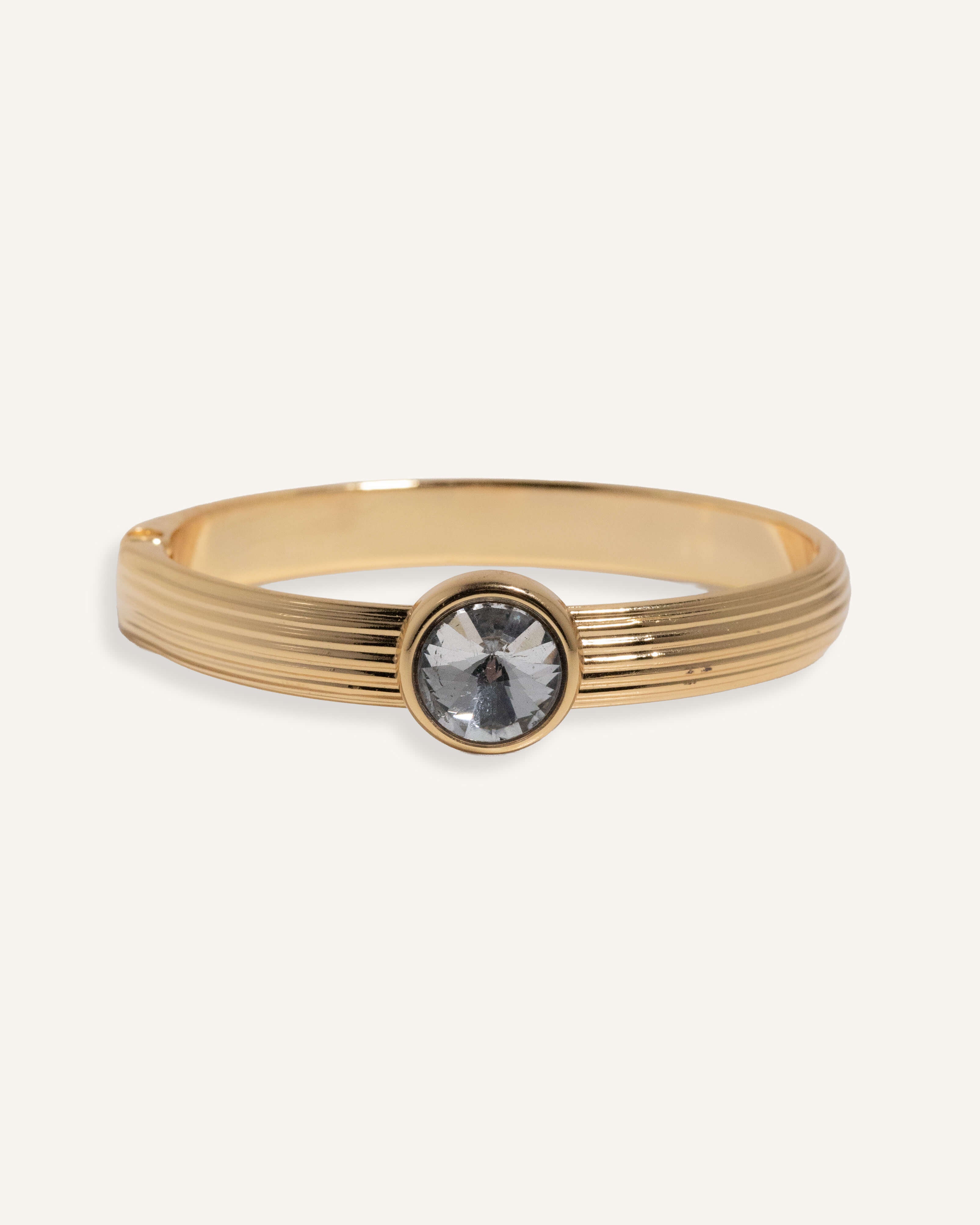  Gold cuff bracelet with ridged band and clear round gemstone at center