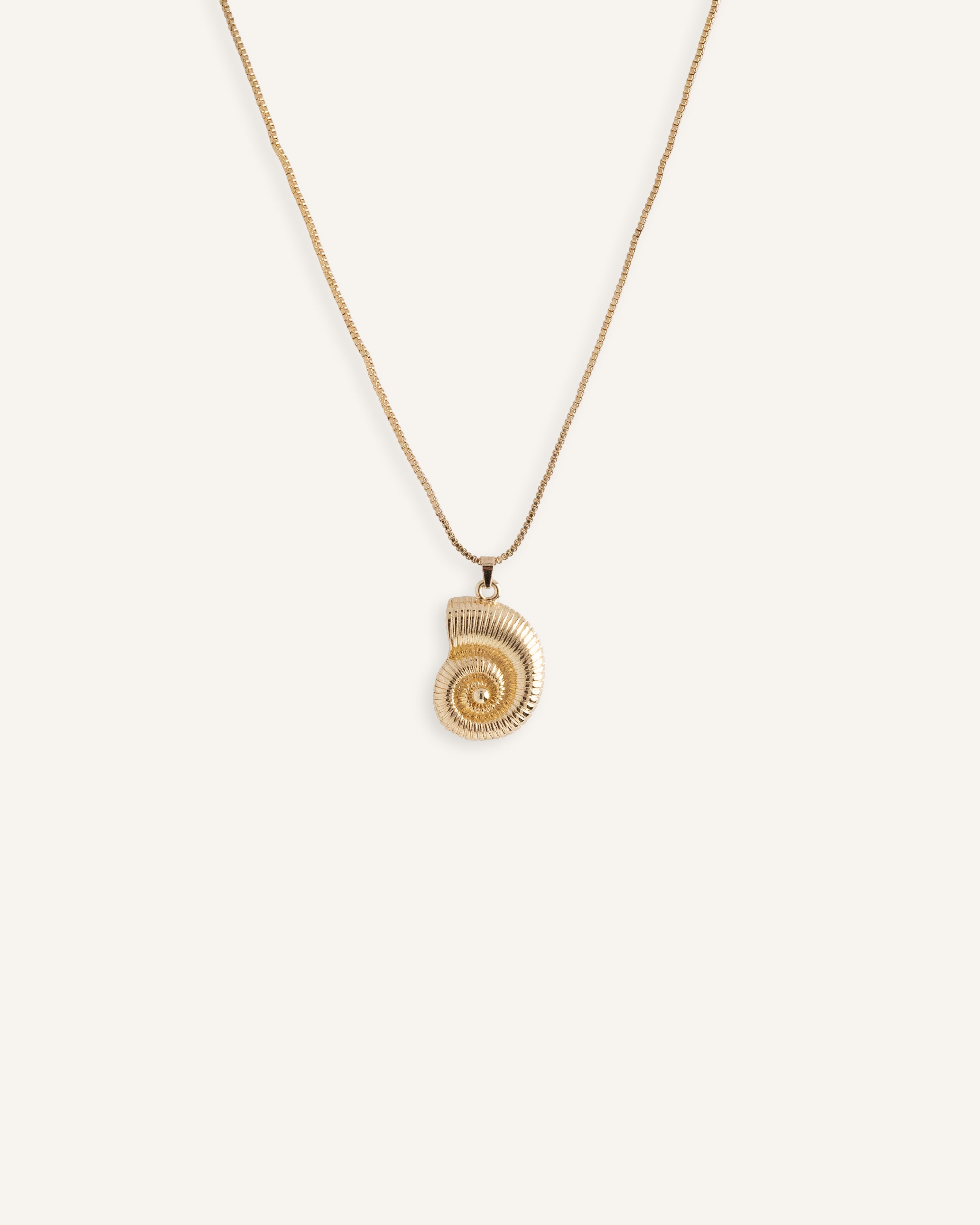 Woman wearing matching gold spiral earrings and necklace with swirl design, styled against a blue background.