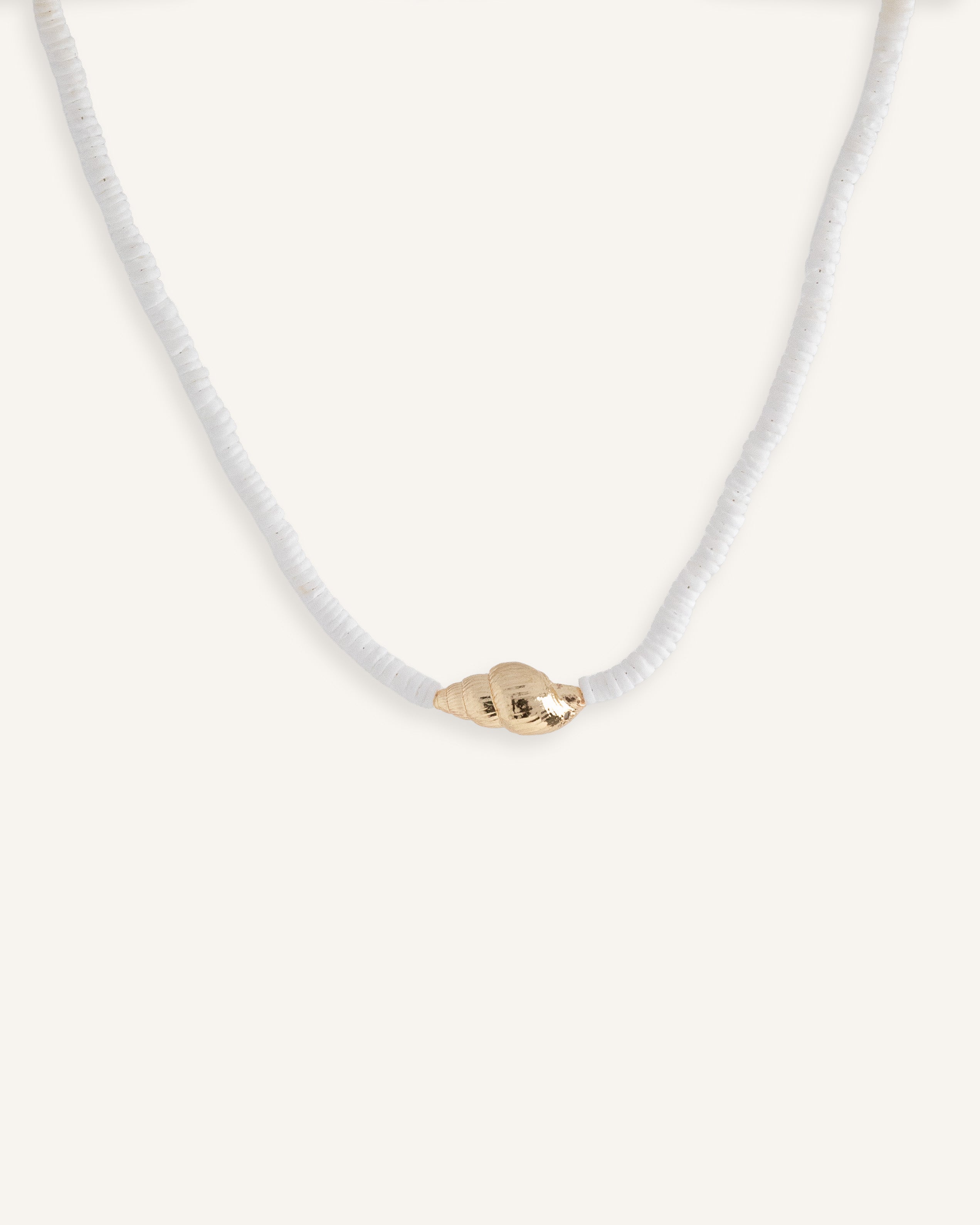 White beaded necklace with gold shell pendant, styled for summer jewelry collection.
