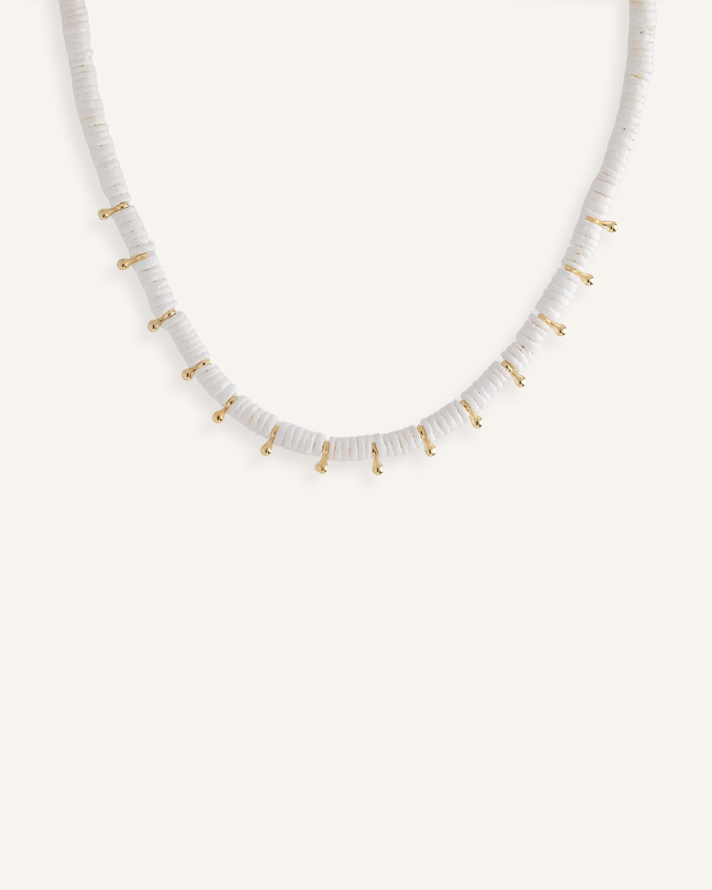 White disc bead necklace with gold drops, styled for a clean summer look.