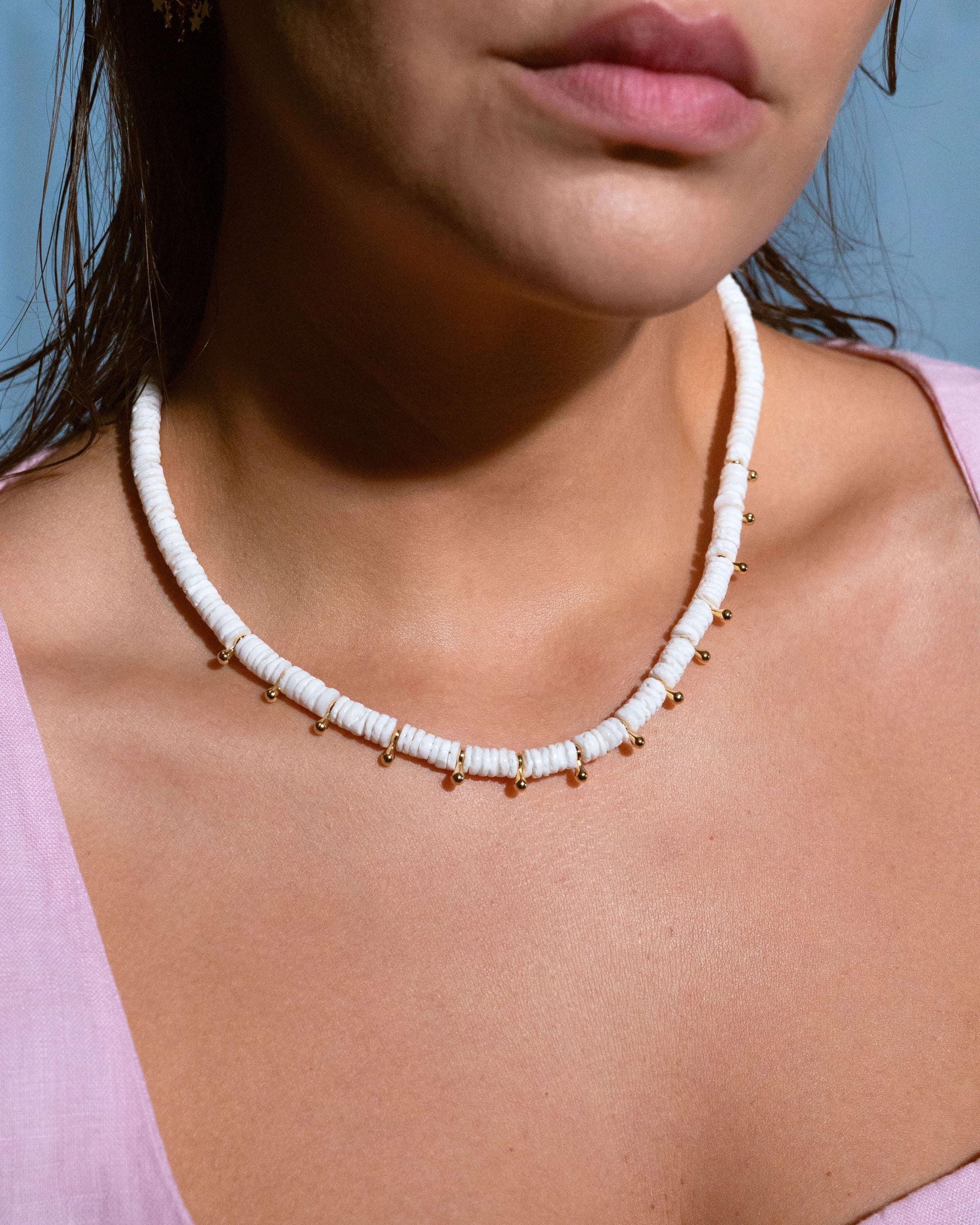 Model wearing white heishi bead necklace with gold accents, stylish boho summer jewelry look, perfect for beach outfits and vacations