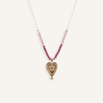 Delicate 14k gold evil eye necklace with red beads on a thin gold chain.