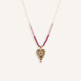 Delicate 14k gold evil eye necklace with red beads on a thin gold chain.