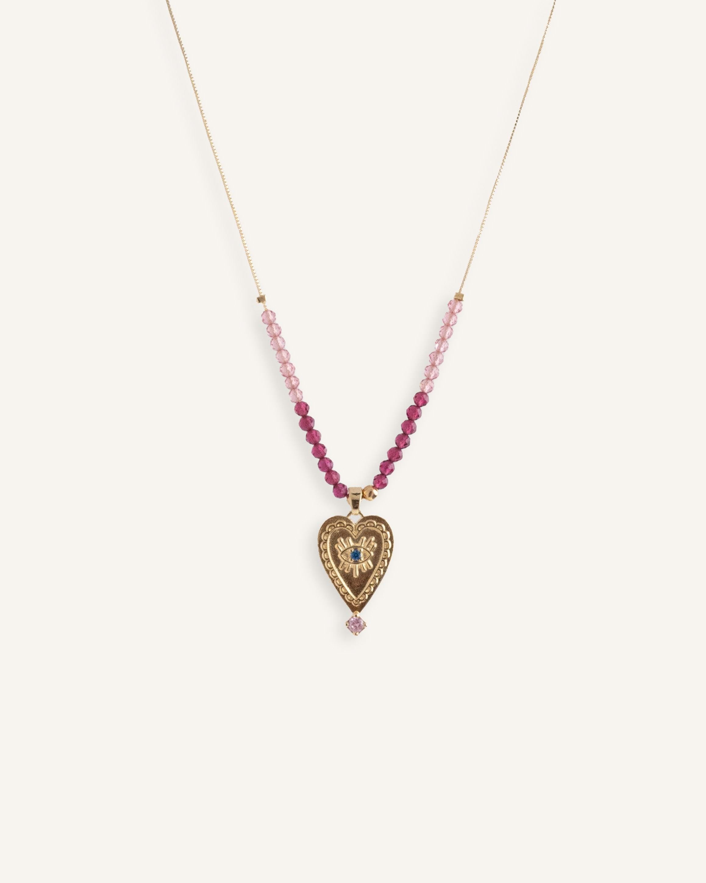 Delicate 14k gold evil eye necklace with red beads on a thin gold chain.