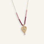 Delicate 14k gold evil eye necklace with red beads on a thin gold chain.