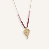 Delicate 14k gold evil eye necklace with red beads on a thin gold chain.