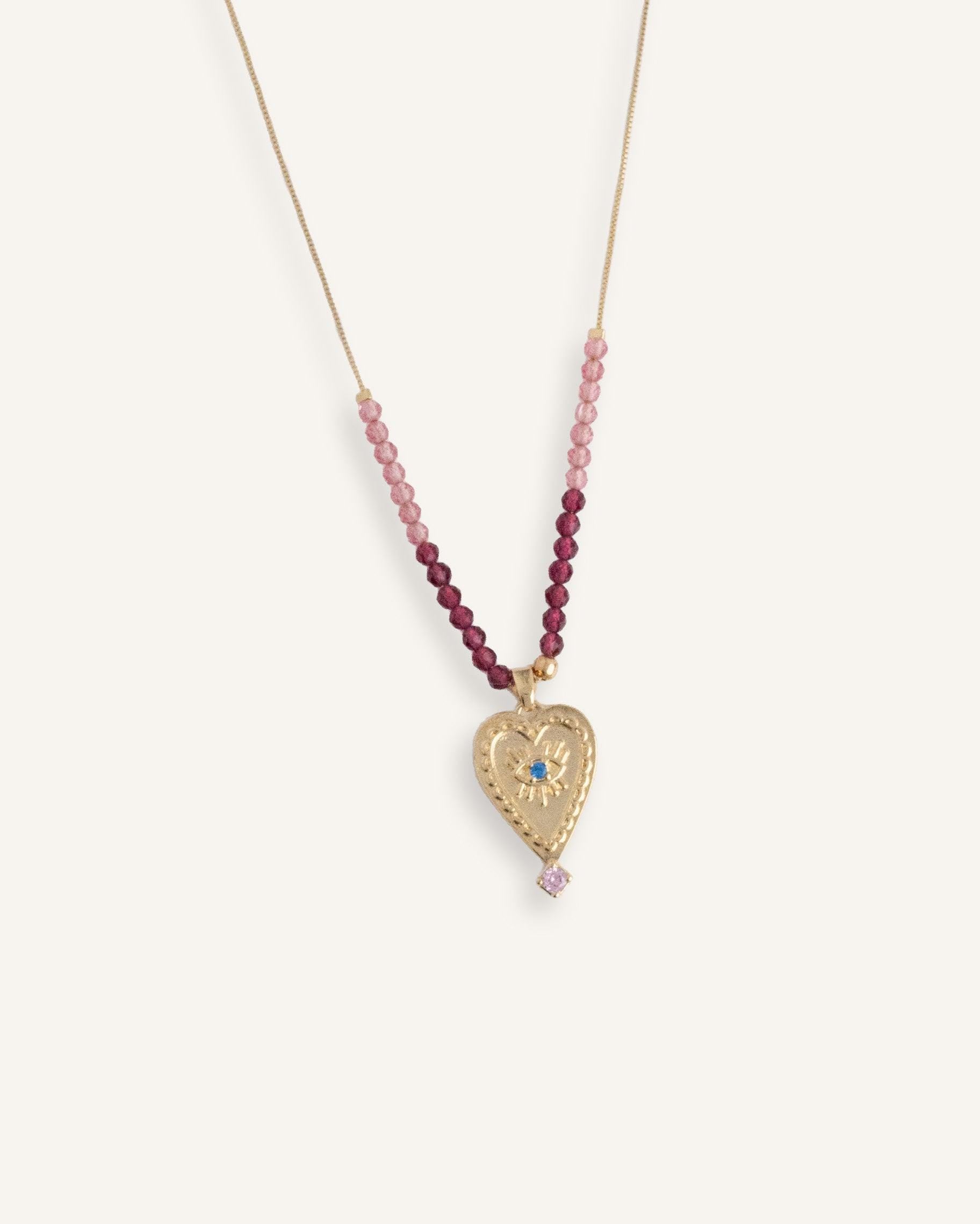Delicate 14k gold evil eye necklace with red beads on a thin gold chain.