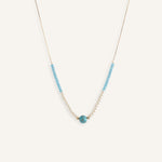 Pearl choker necklace with turquoise bead details, styled on a neutral background.