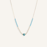 Pearl choker necklace with turquoise bead details, styled on a neutral background.