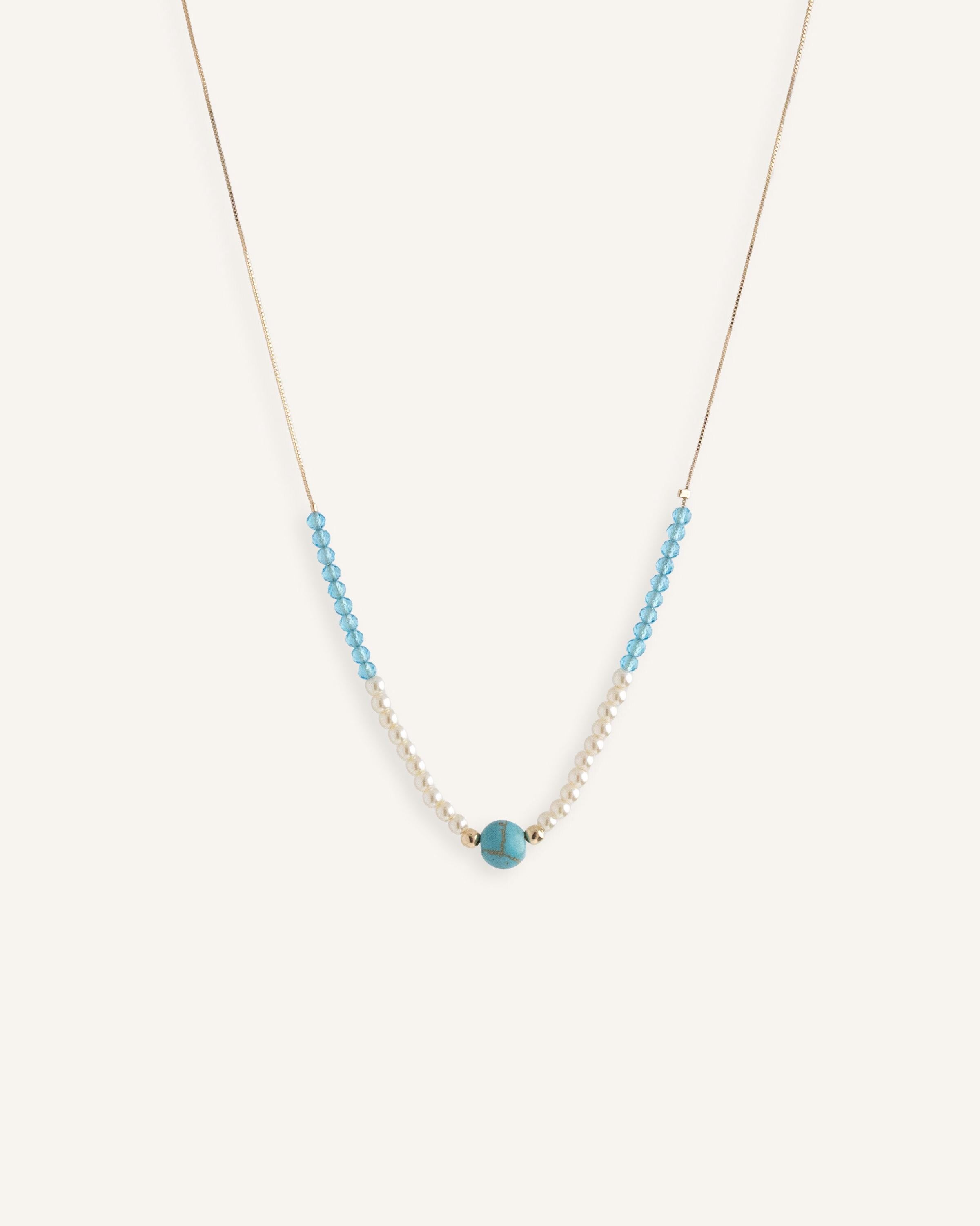 Pearl choker necklace with turquoise bead details, styled on a neutral background.