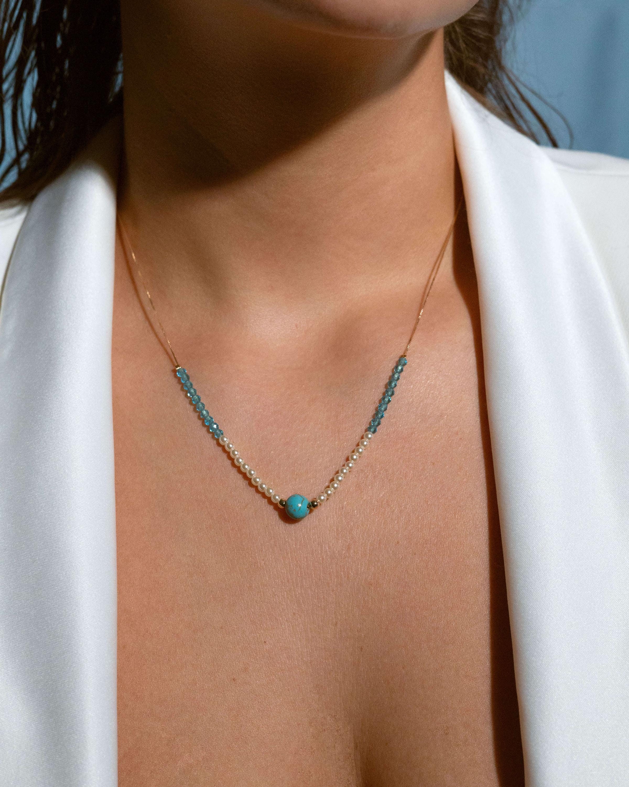 Model wearing turquoise and pearl beaded necklace with gold chain, layered summer jewelry look, perfect for casual outfits or vacation style