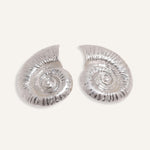 Bold shell earrings in gold and silver, styled for an ocean-inspired summer collection.