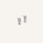 Pair of silver stud earrings with baguette crystal tops and pearl drops, displayed on a soft background.