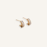 Pair of gold stud earrings with curved crystal fan design, displayed on a neutral background.