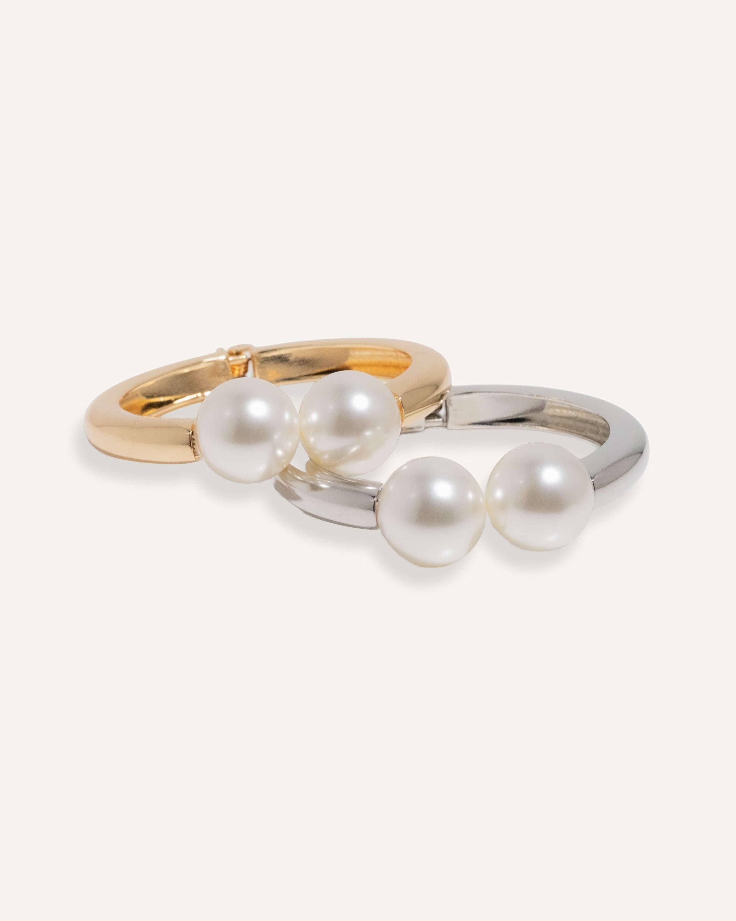 Hinged cuff bracelet with two pearl accents, shown in gold-plated and silver finishes.