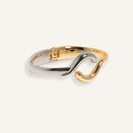 Two-tone bracelet in silver and gold with wave crossover design, styled for minimalist everyday wear