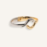 Two-tone bracelet in silver and gold with wave crossover design, styled for minimalist everyday wear