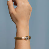 Gold plated bangle bracelet with grooved texture and a round clear crystal centerpiece – minimalist and elegant cuff for women