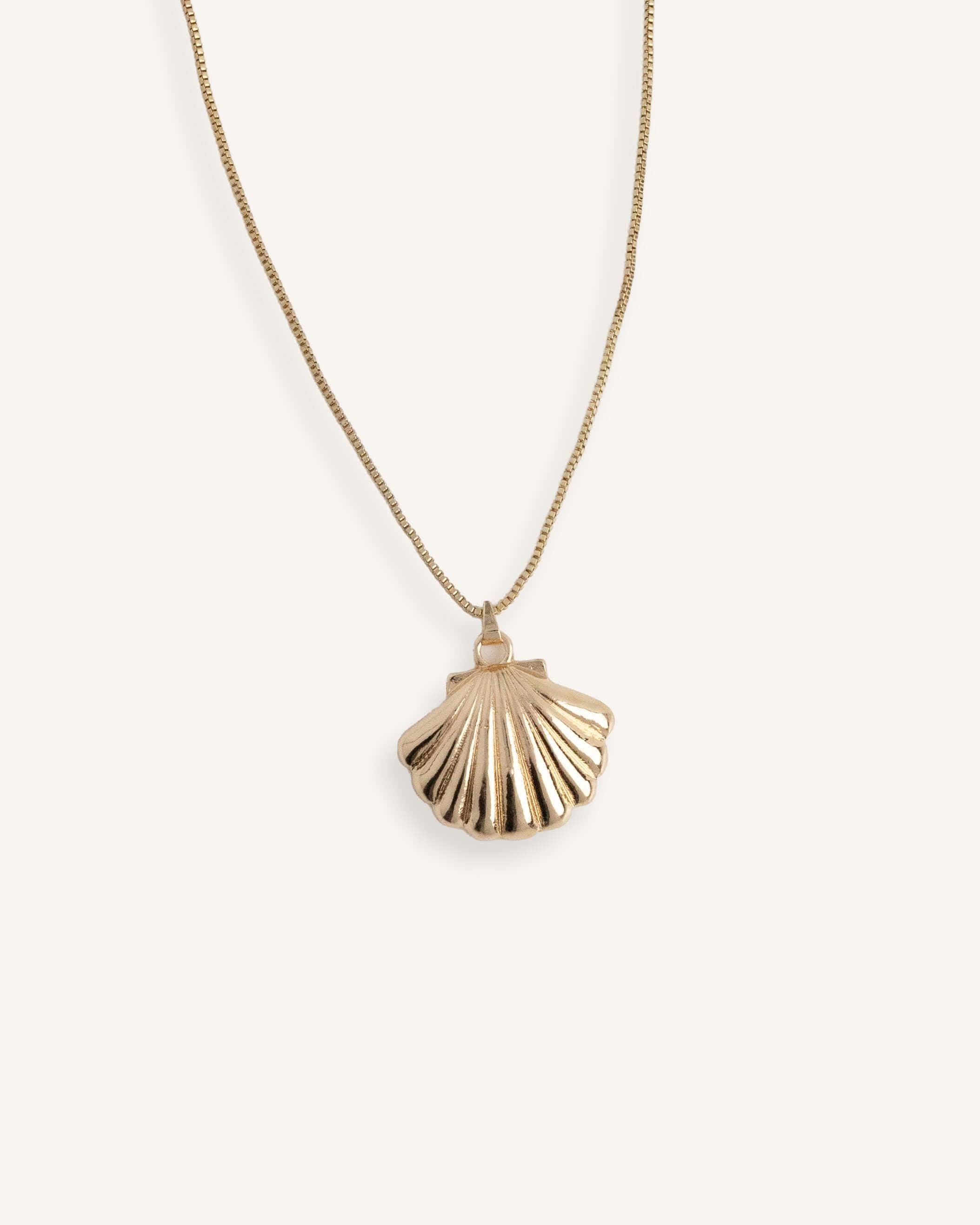 Minimal gold necklace with shell-shaped pendant.