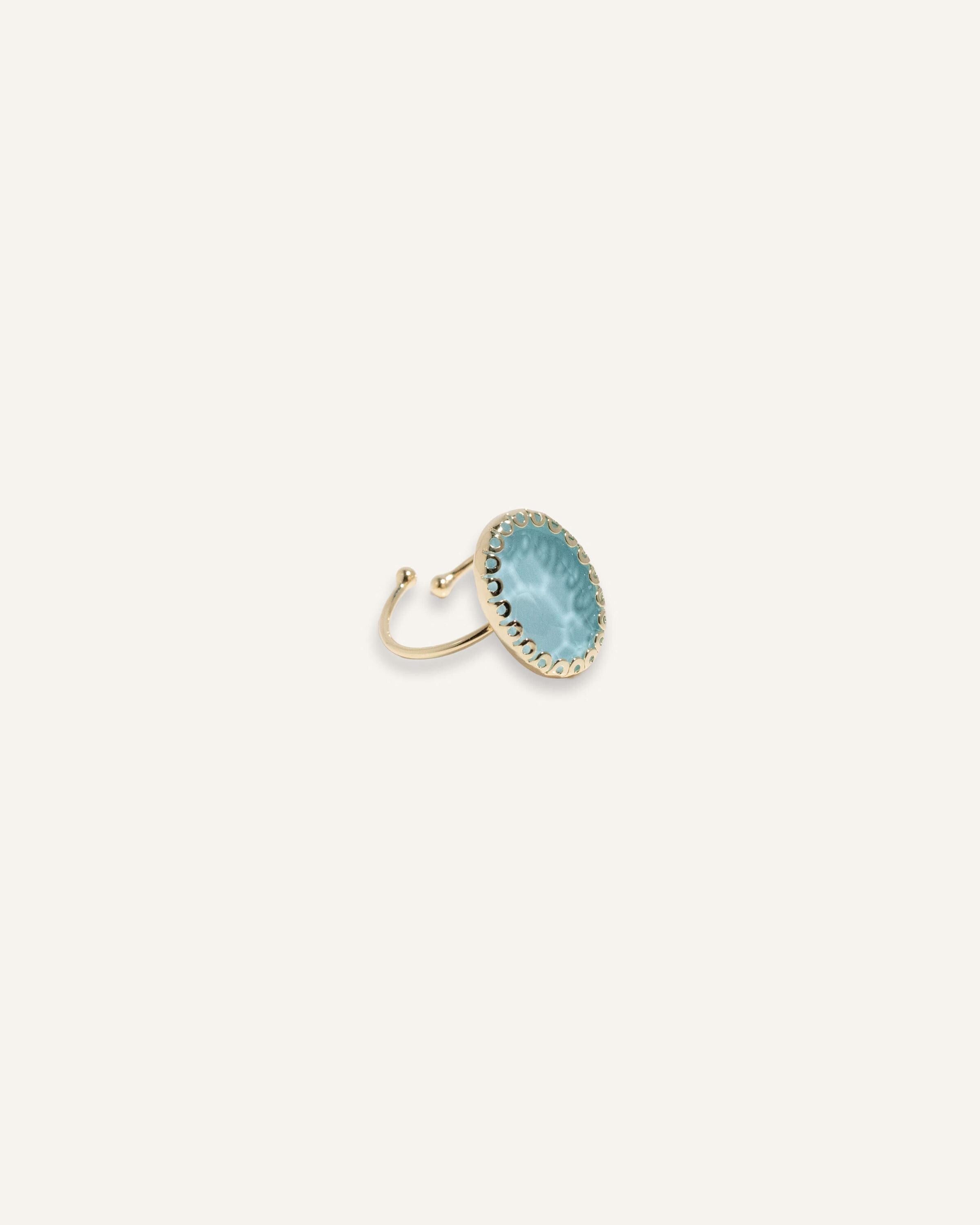 Gold adjustable ring with a red or blue stone, styled with a modern bold shape.