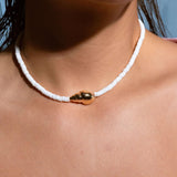 Model wearing dainty white beaded necklace with gold shell charm, casual summer jewelry for beach days, vacation outfit accessory