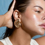 Gold plated nautilus shell stud earrings with a shiny finish, beach-themed statement jewelry, spiral seashell earrings for summer outfits