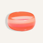 Chunky resin bangle in coral and pink gradient stripes, styled as a bold summer accessory.