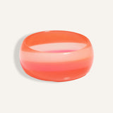 Chunky resin bangle in coral and pink gradient stripes, styled as a bold summer accessory.