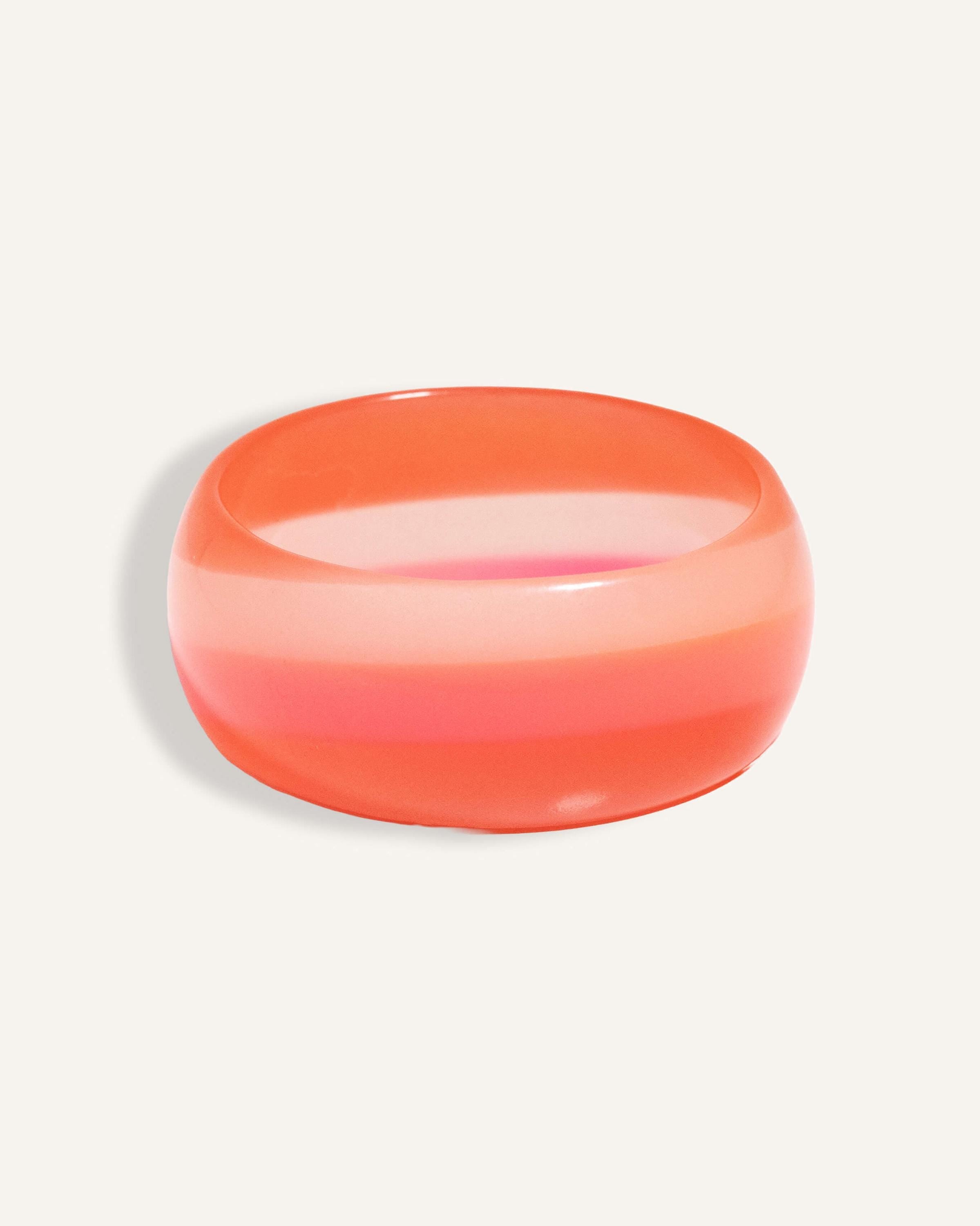 Chunky resin bangle in coral and pink gradient stripes, styled as a bold summer accessory.