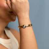 Gold plated bangle bracelet with grooved texture and a round clear crystal centerpiece – minimalist and elegant cuff for women.