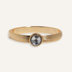 Gold cuff bracelet with ridged band and clear round gemstone at center
