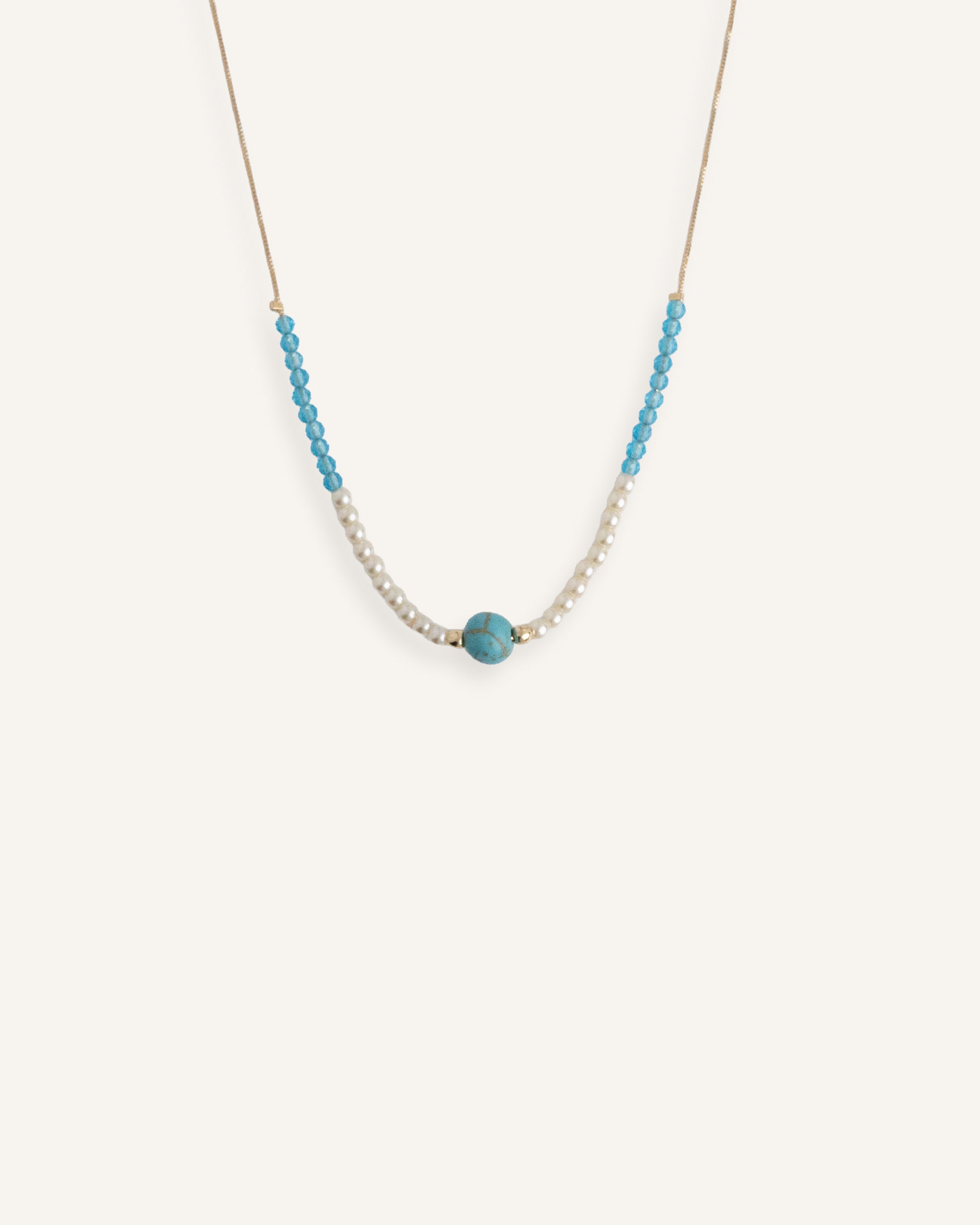 Pearl choker necklace with turquoise bead details, styled on a neutral background.
