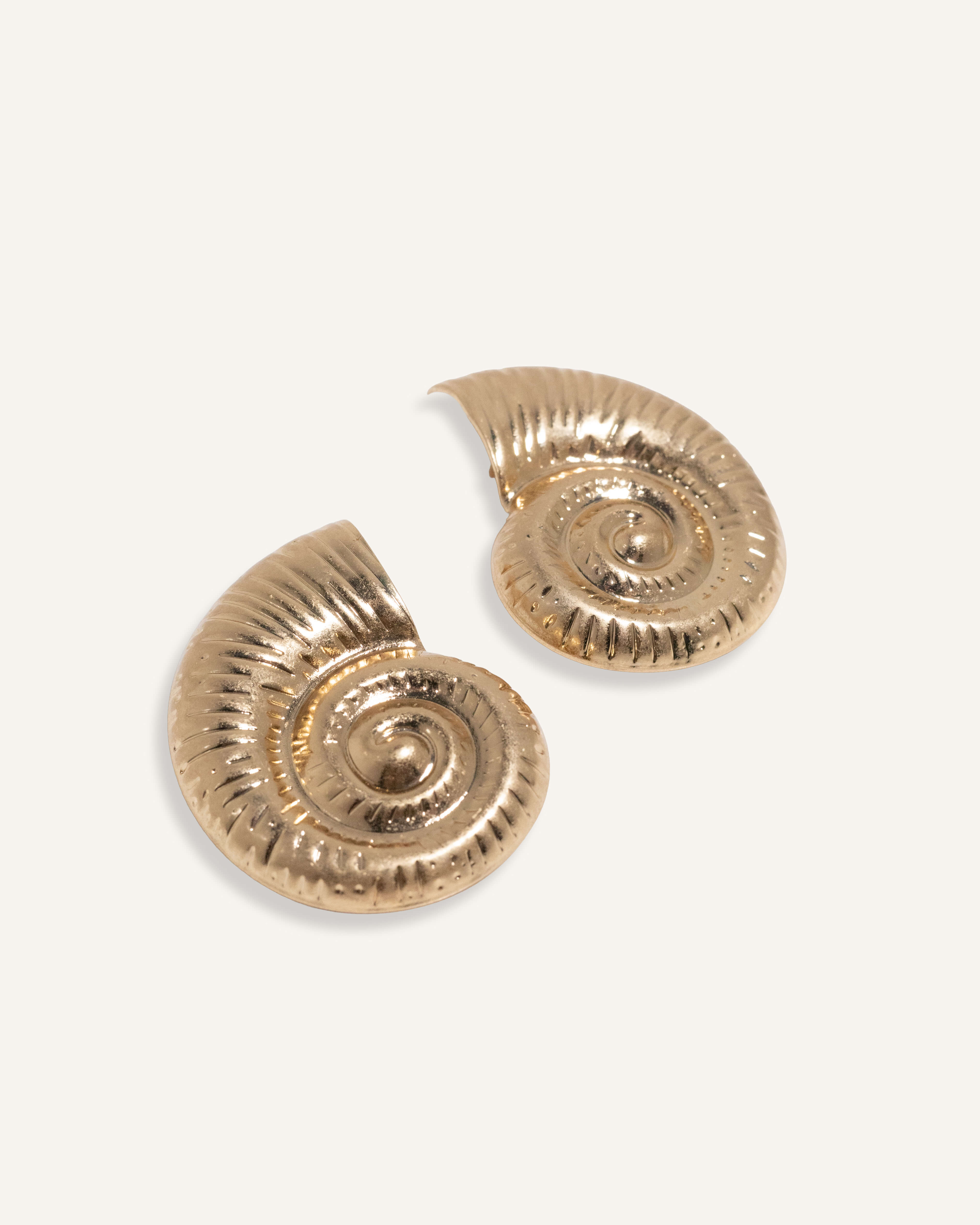 Bold shell earrings in gold and silver, styled for an ocean-inspired summer collection.
