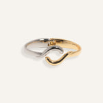 Two-tone bracelet in silver and gold with wave crossover design, styled for minimalist everyday wear.