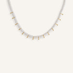  White disc bead necklace with gold drops, styled for a clean summer look.