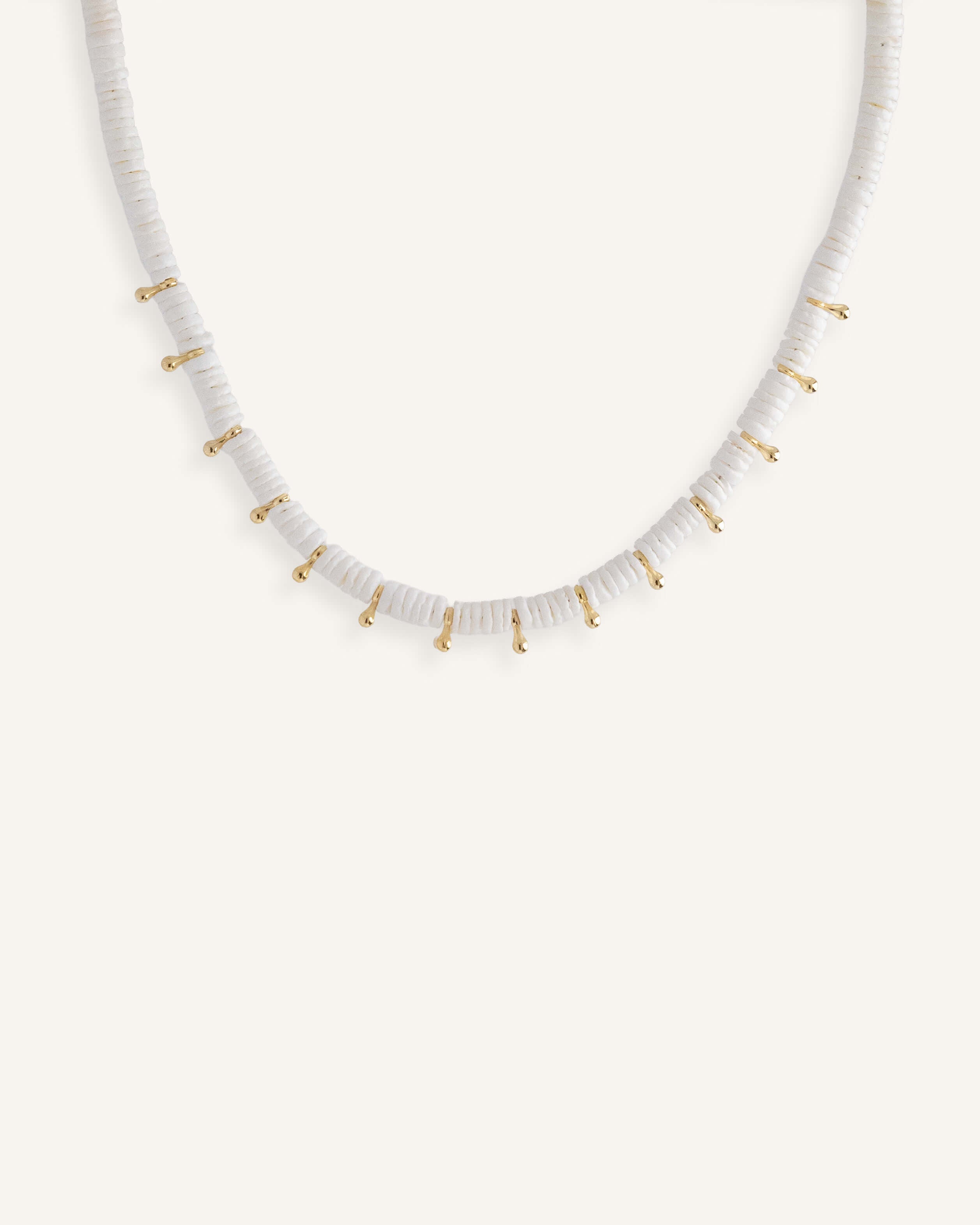  White disc bead necklace with gold drops, styled for a clean summer look.
